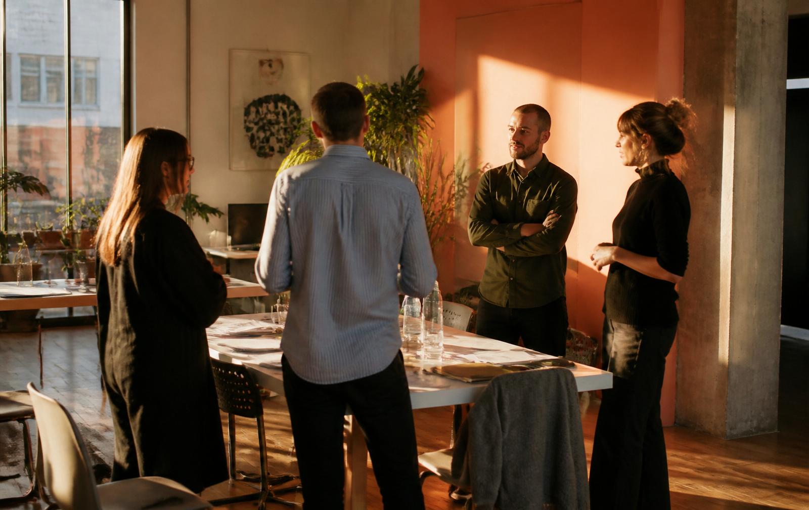 A small team standing around a working table in late afternoon light